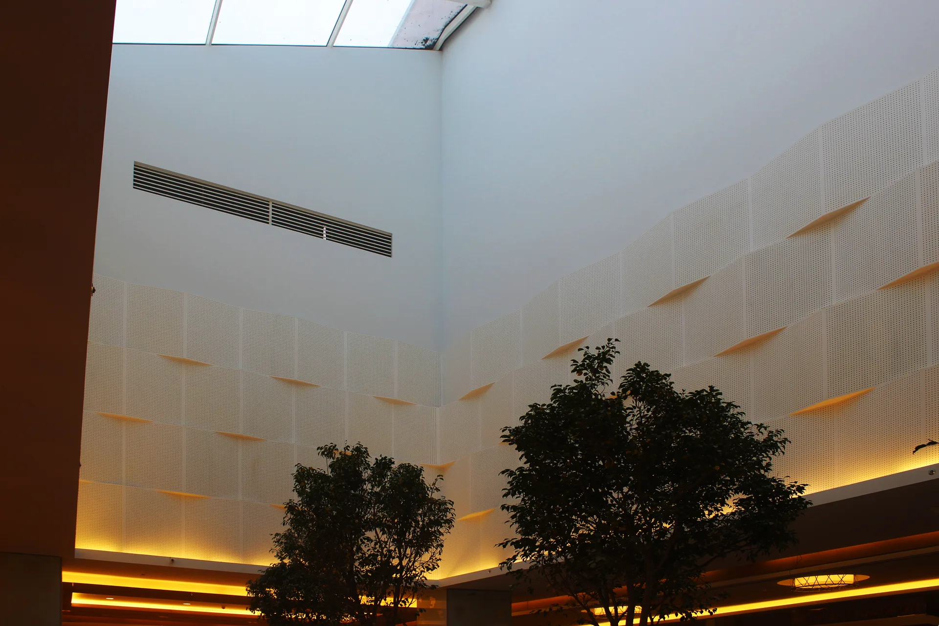 Full-height textured wall panels lit from below beside the atrium rooflight