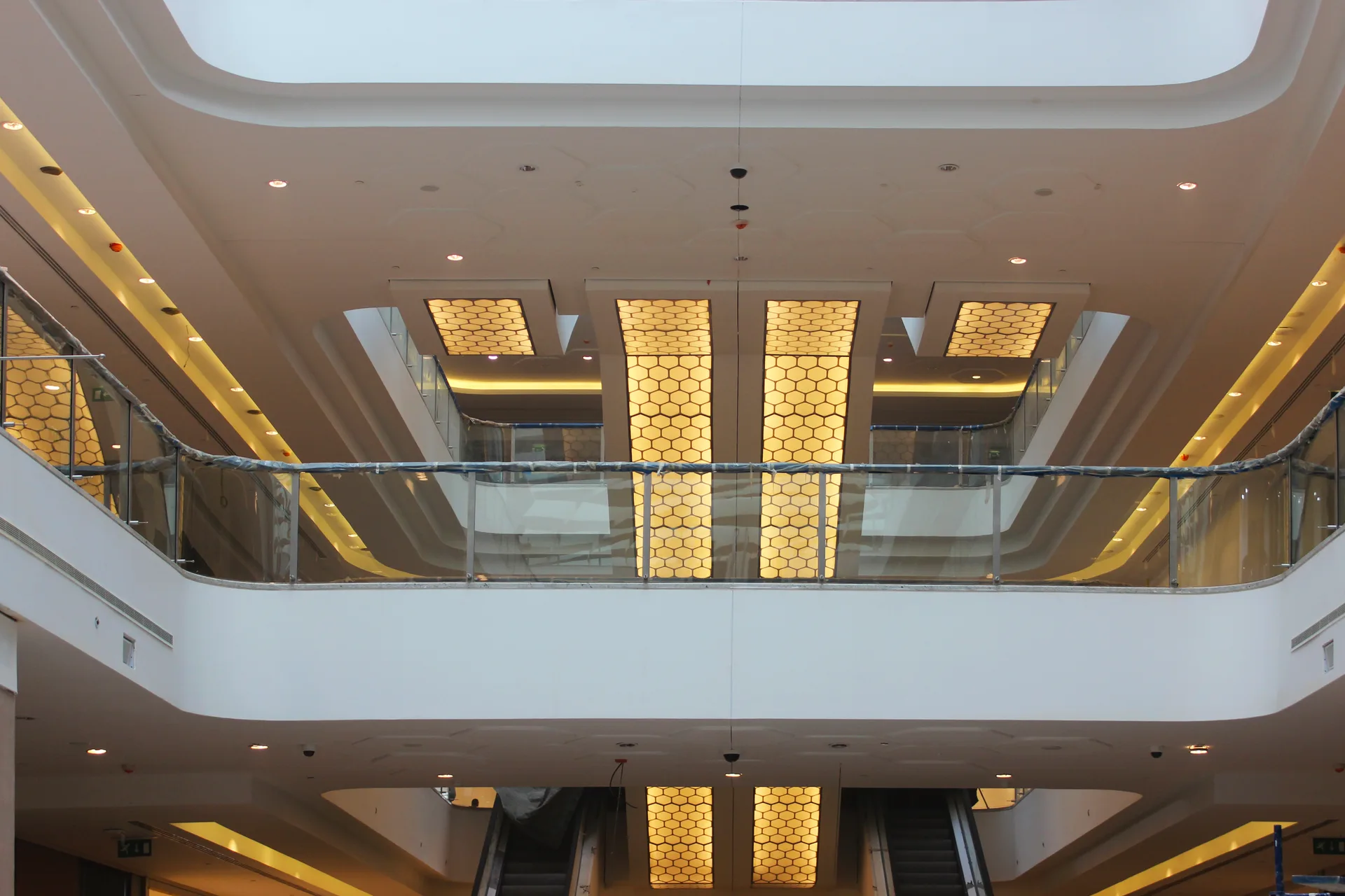 Atrium balconies with backlit honeycomb panels between the escalator runs