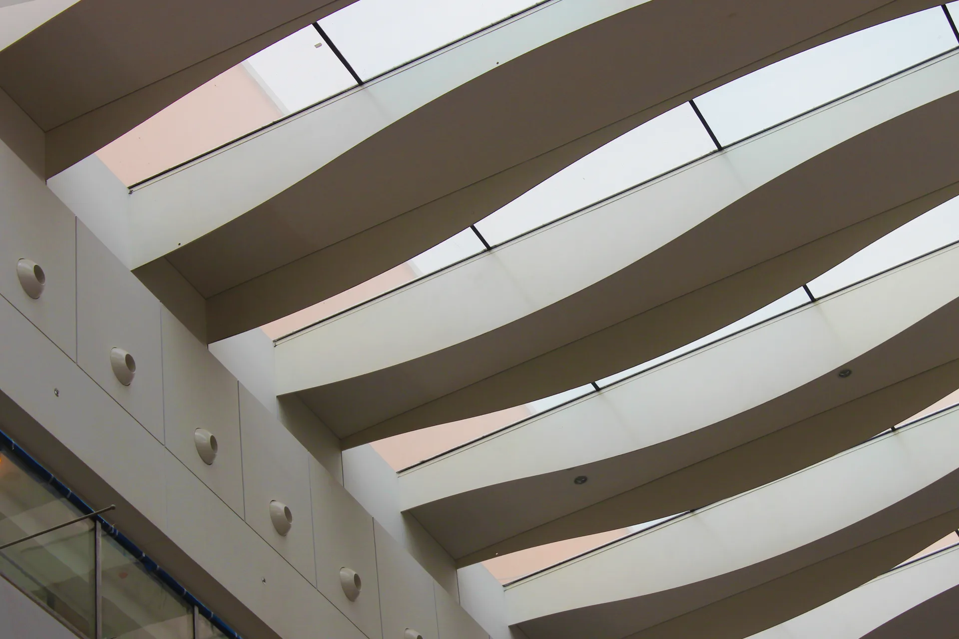 Wave-profile ceiling blades meeting the rooflight glazing