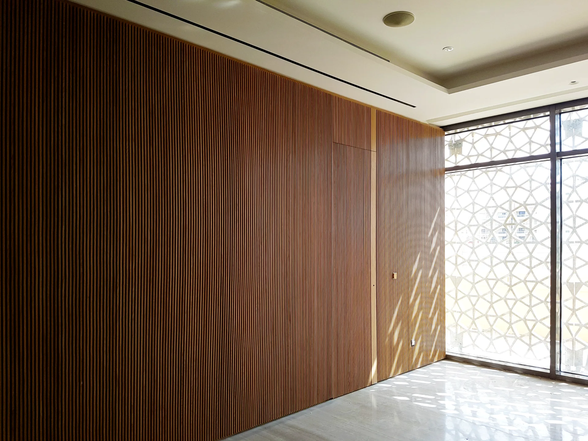 Fluted timber wall panelling beside a patterned mashrabiya screen