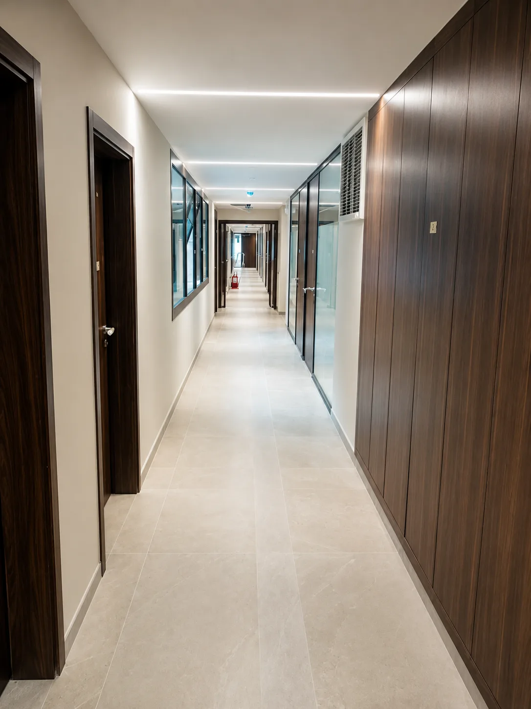 Office corridor lined with dark timber panelling, glazed partitions and a continuous light cove
