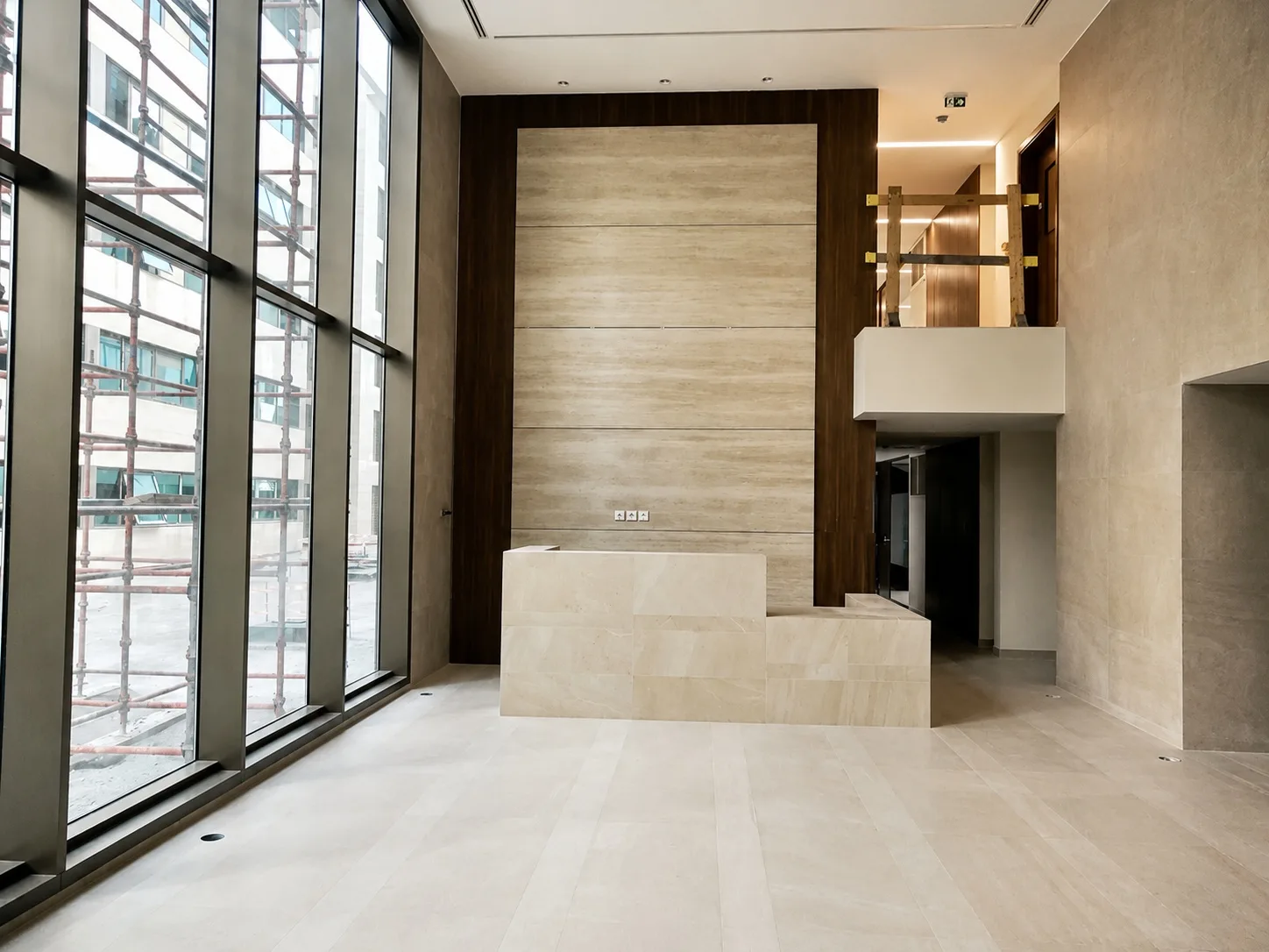 Double-height entrance lobby — travertine reception desk against a stone and dark-timber wall