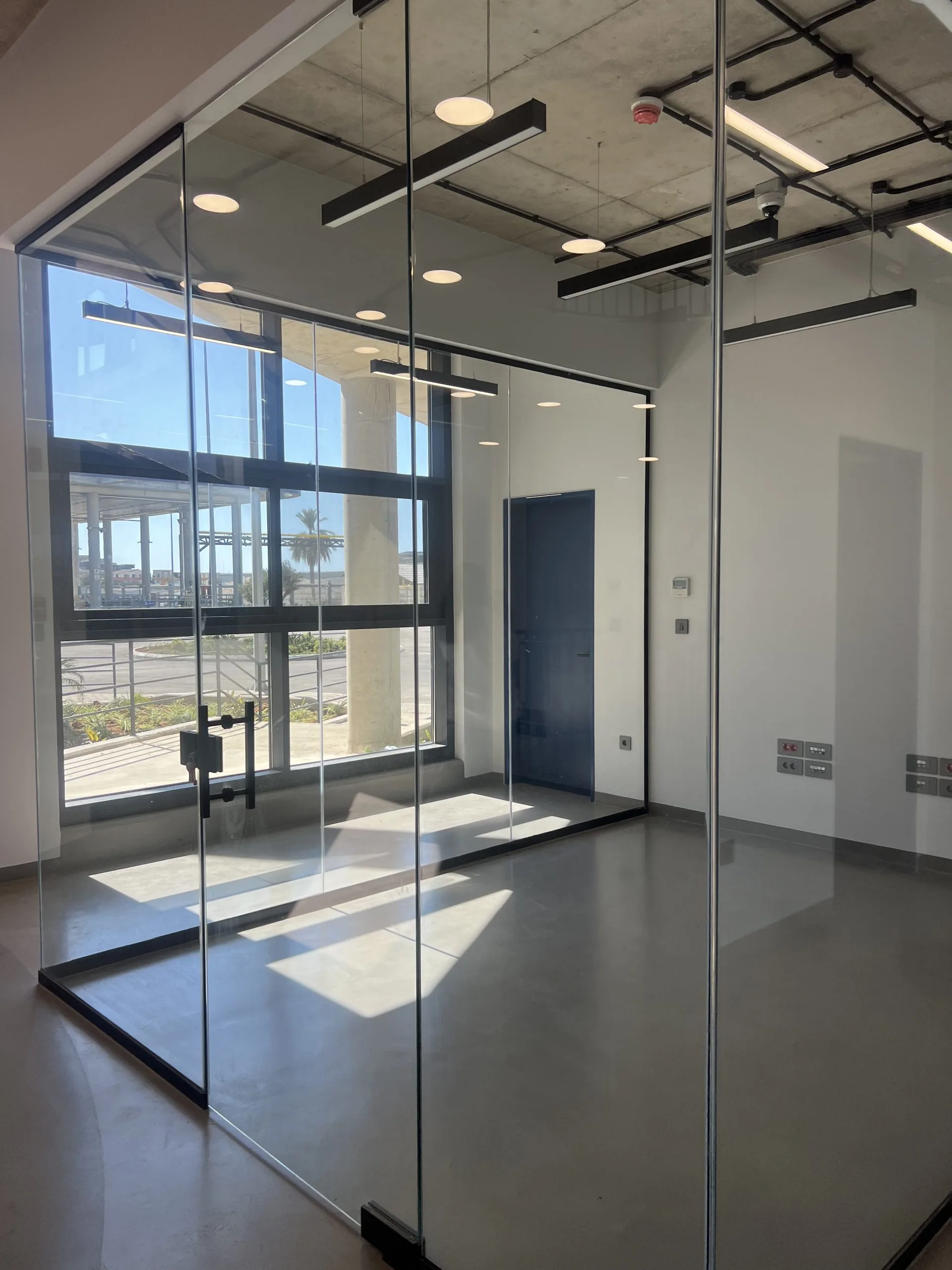 Glazed meeting room enclosure with exposed black service runs above