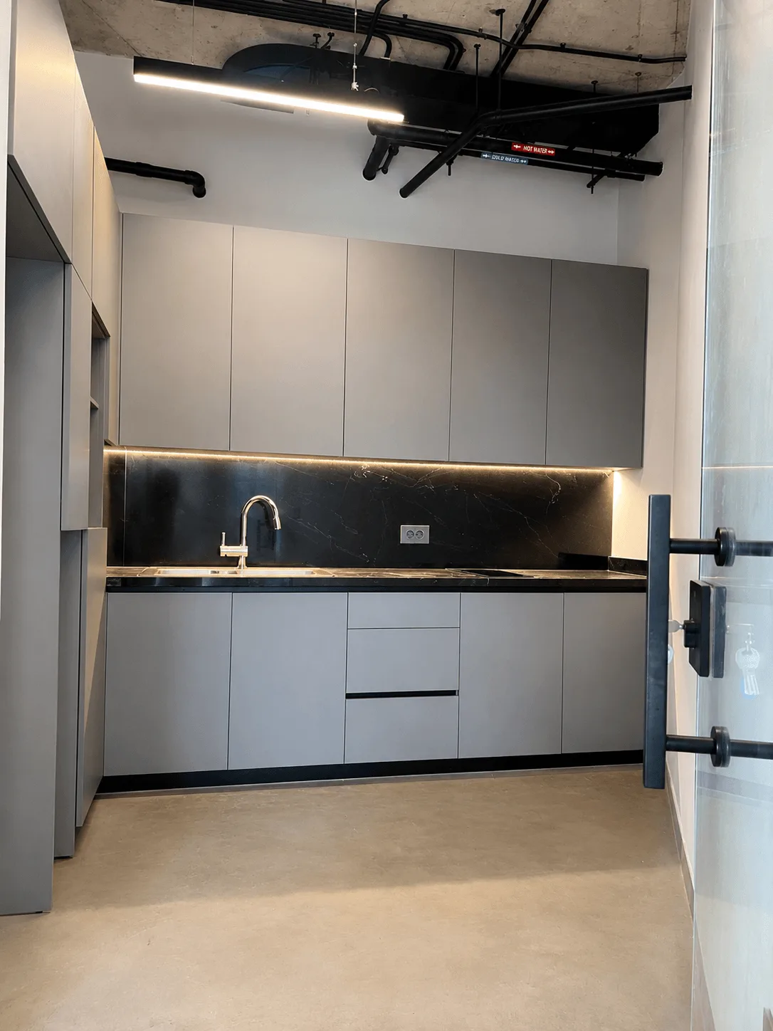 Fitted pantry — grey joinery with a dark stone splashback and worktop