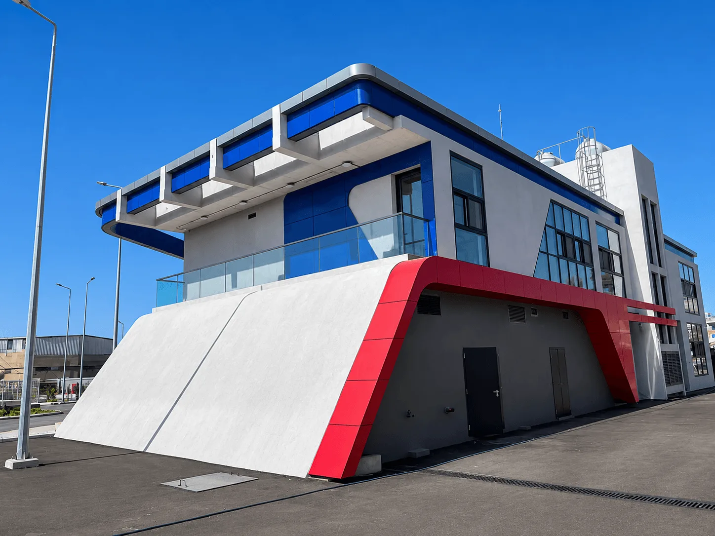 Administration building — red and white sculpted ramp wall under the blue cornice