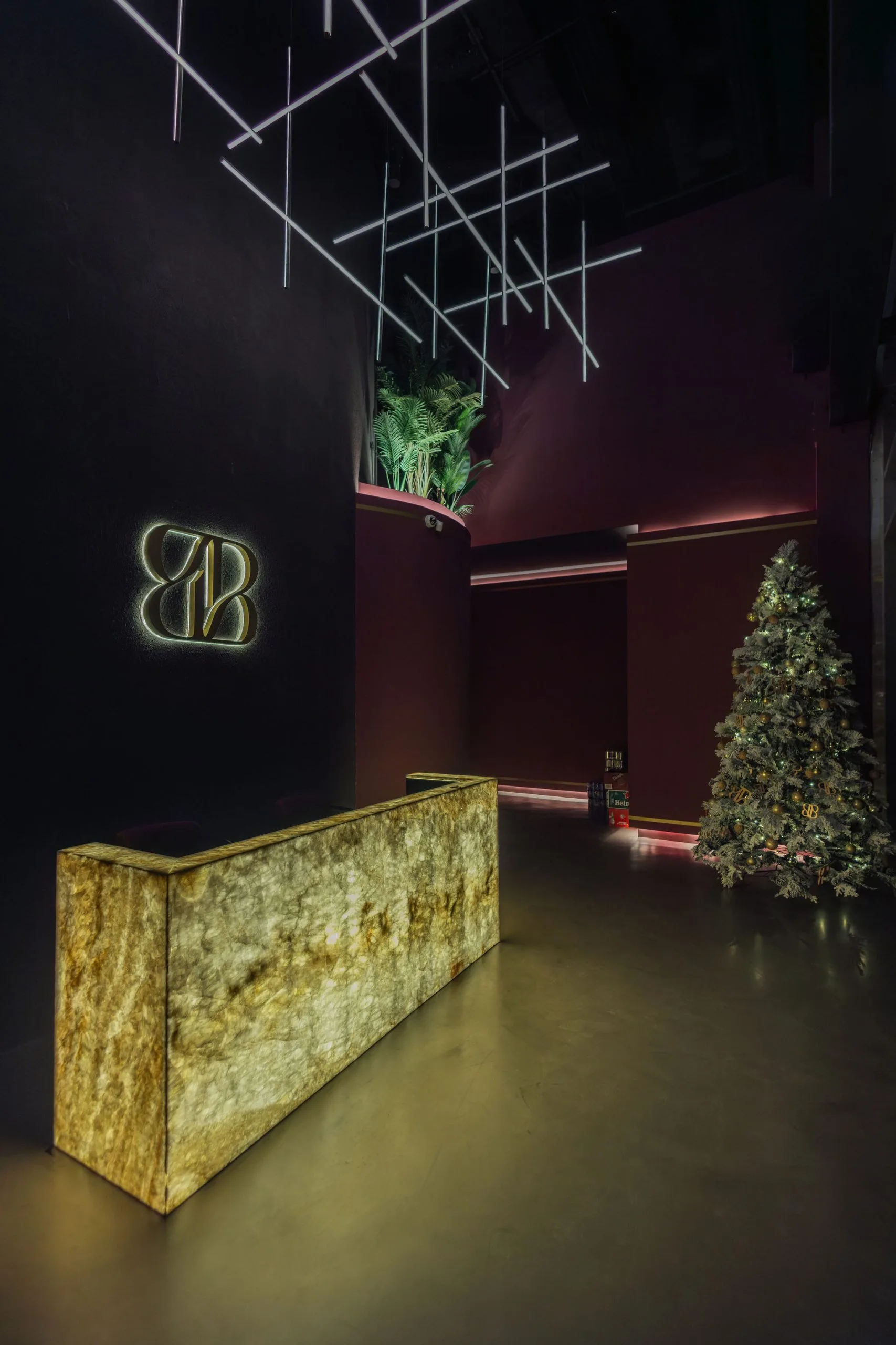 Entrance hall with a backlit onyx reception desk beneath a linear light sculpture
