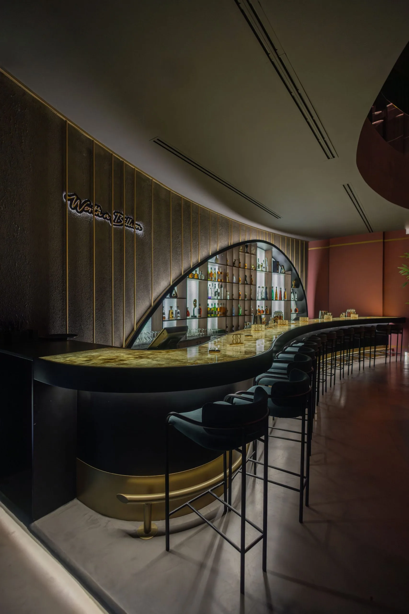 Curved bar with a backlit onyx counter and an arched bottle display
