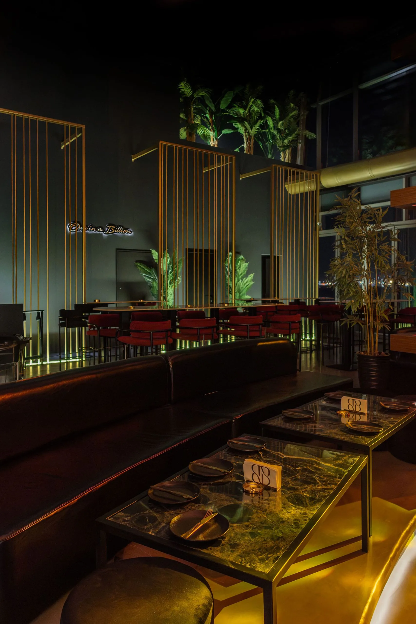 Banquette seating framed by brass screens and planting