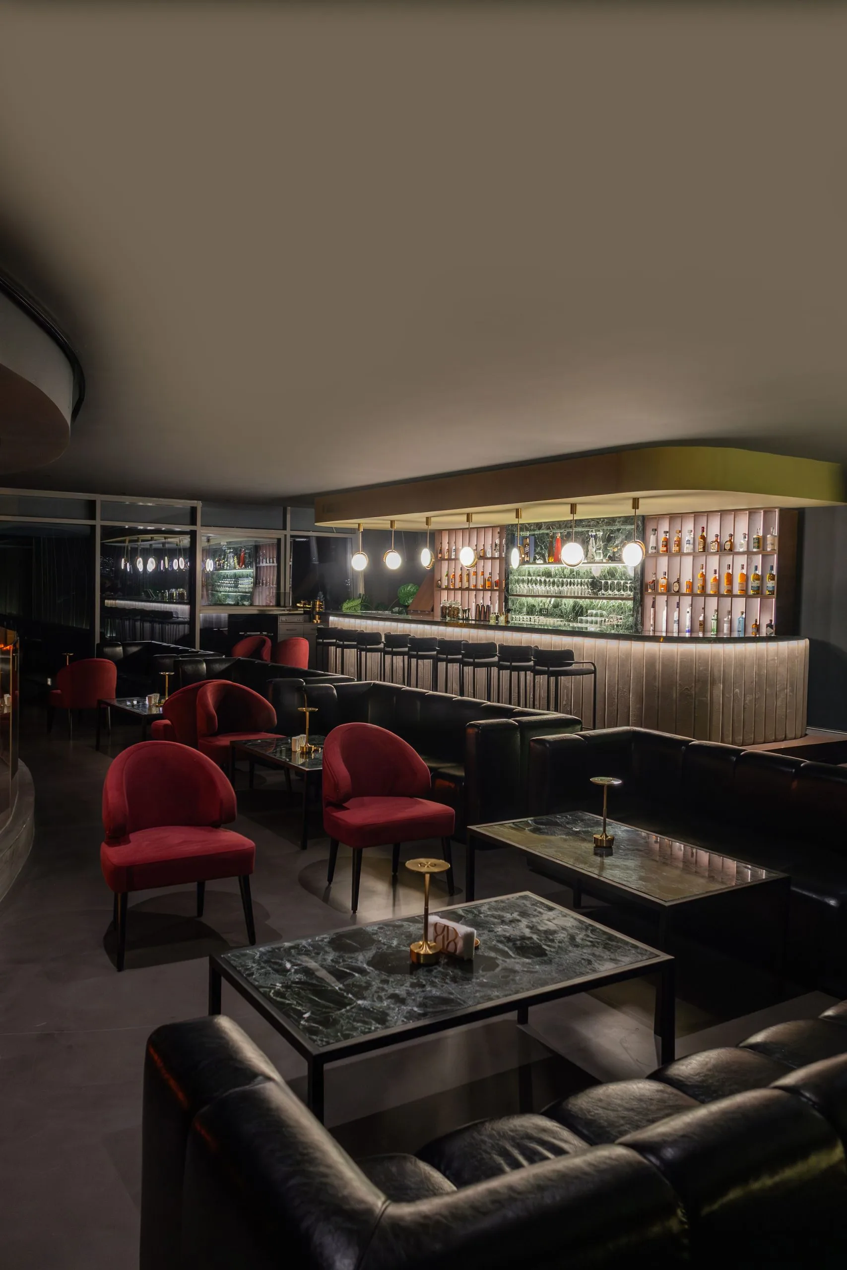 Lounge bar — red velvet chairs, marble tables and a lit back bar
