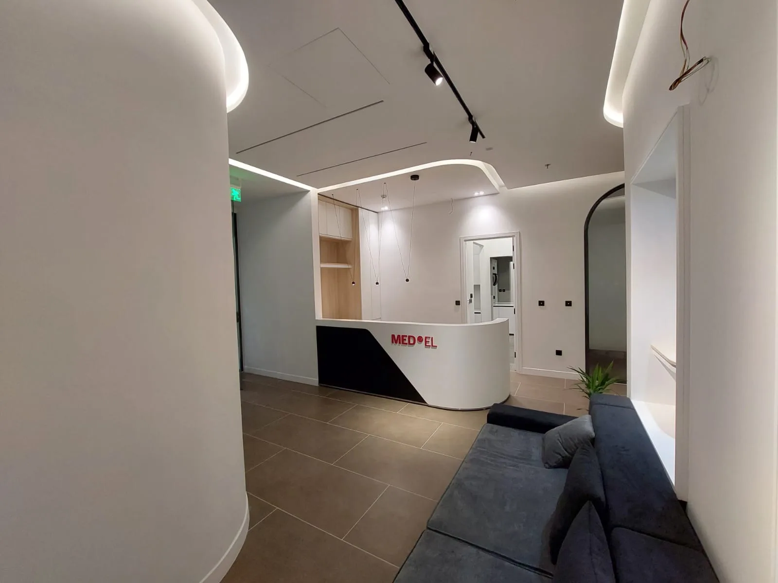 Reception desk set against a curved wall with a concealed cove running the ceiling
