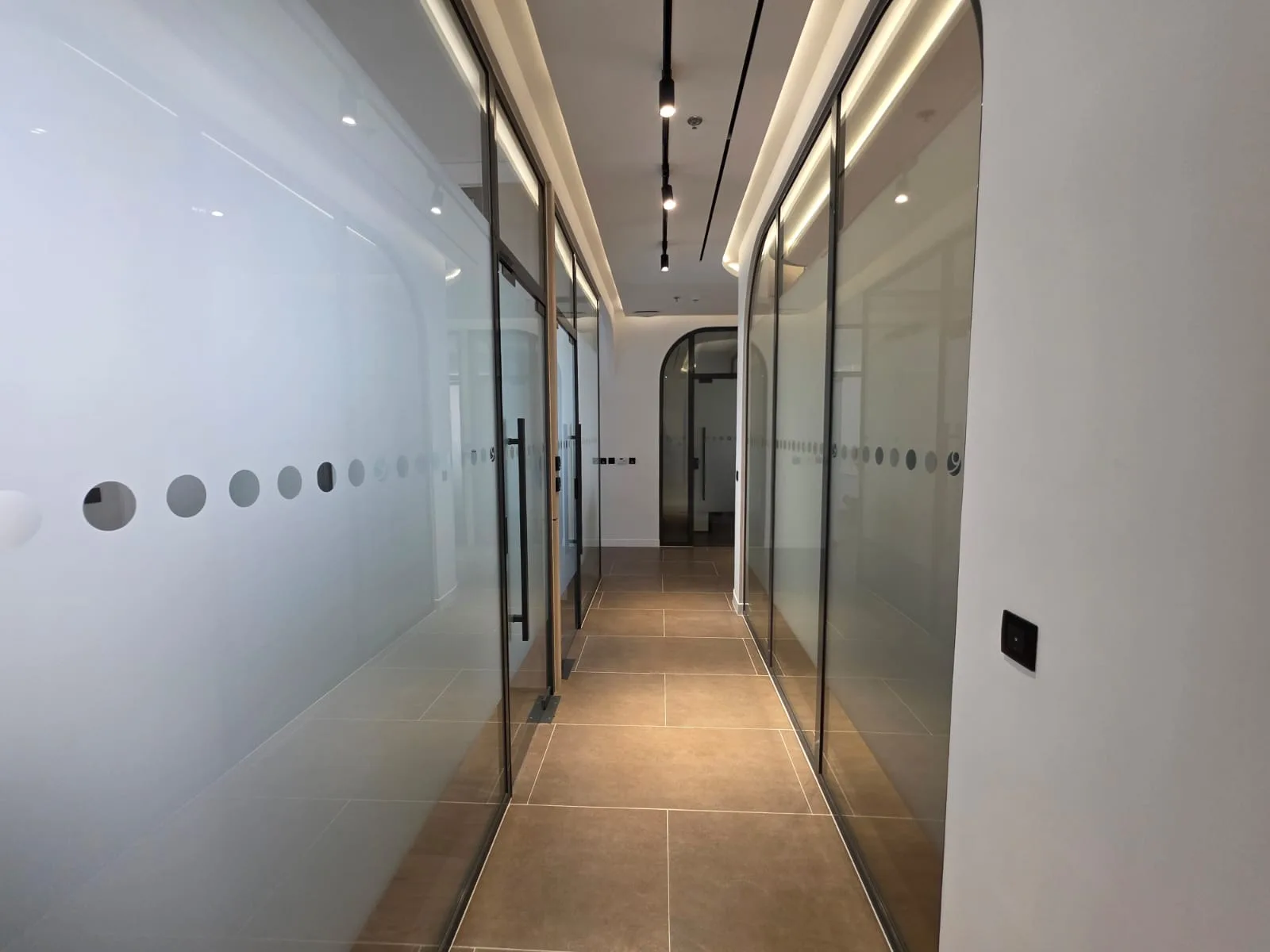Corridor between frosted glass partitions under a lit ceiling recess